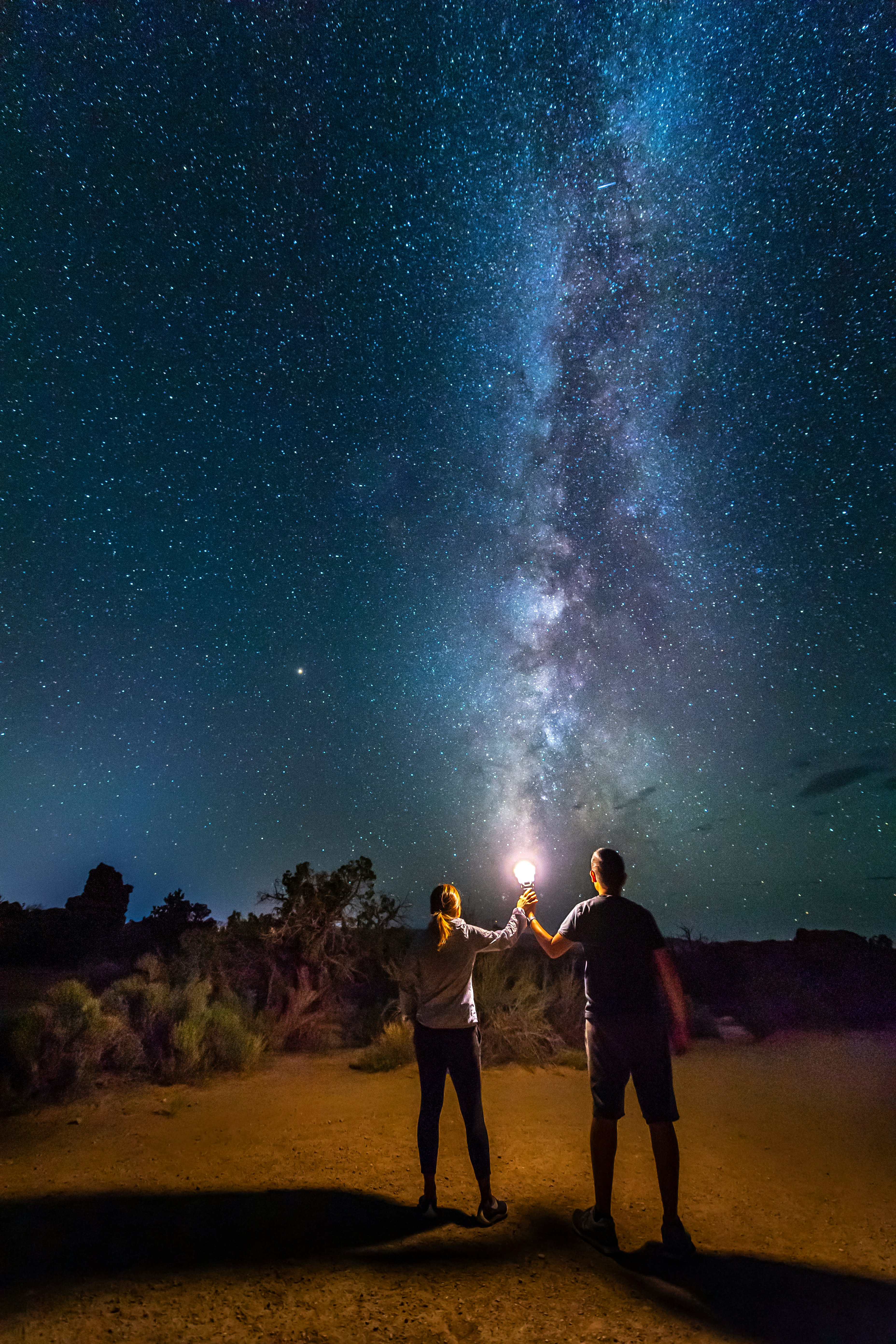 people standing on brown sand under starry night